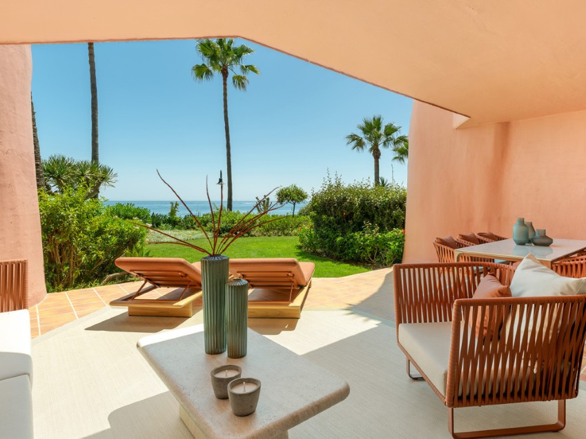Apartamento en primera línea de playa en Estepona – Menara Beach Vista de un apartamento en primera línea de playa en Menara Beach, Estepona, con vistas al mar y jardines cuidados.